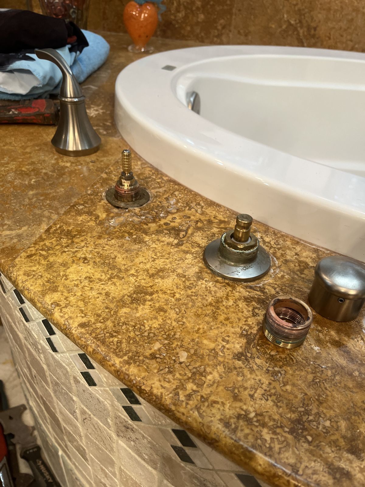 Original roman tub valve cartridges on a marble tub deck before replacement