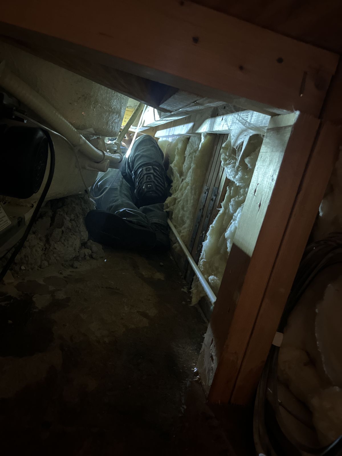 Plumbing technician working in the small access space behind a deck-mounted tub